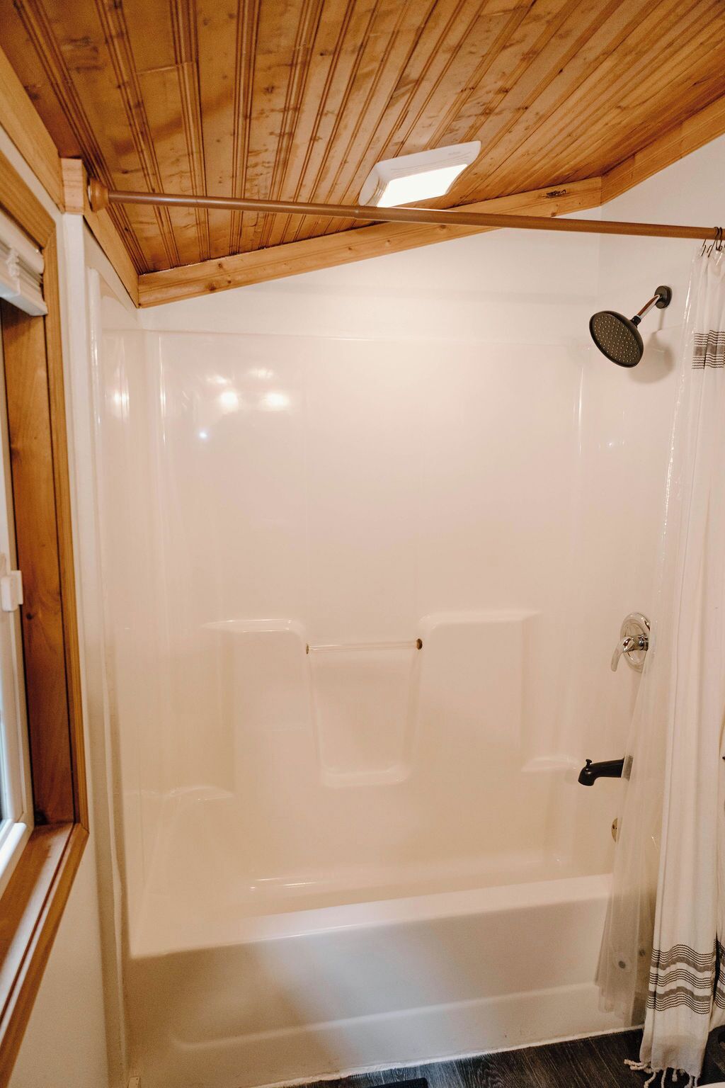A bathroom with a wooden ceiling, a bathtub, and a shower area.