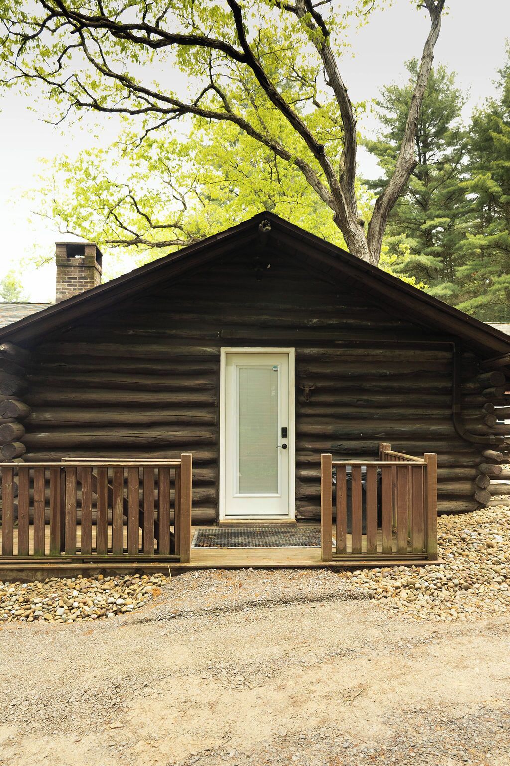 A log cabin with a front door, wooden gate, and a small porch area.