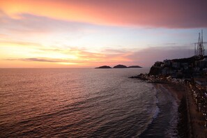 A coastal sunset view with buildings along the shore. - Casa Corsario (Mazatlán)