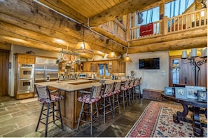 A spacious kitchen with a large island, wooden bar stools, and a rustic ceiling. - SKI-IN/ SKI-OUT WITH GORGEOUS MOUNTAIN VIEWS! (Mountain Village)