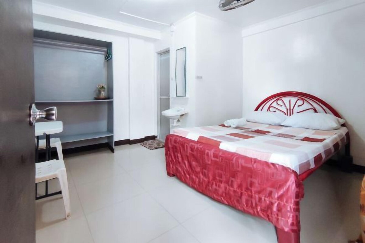 A bedroom with a bed, a white desk, and a wardrobe.