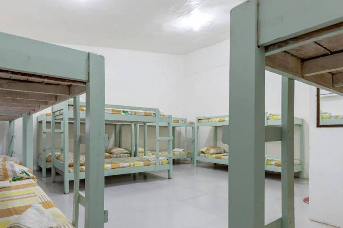 A dormitory room with bunk beds, white walls, and a tiled floor.