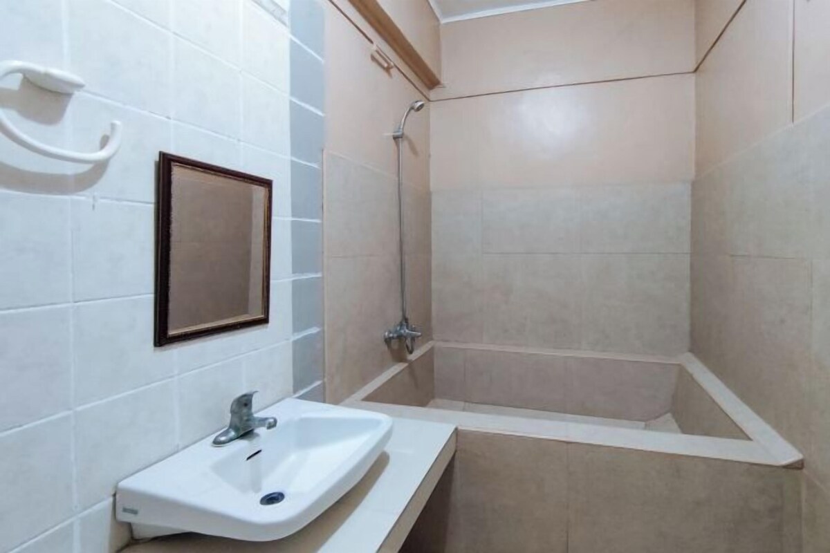 A bathroom with a sink, mirror, and shower.