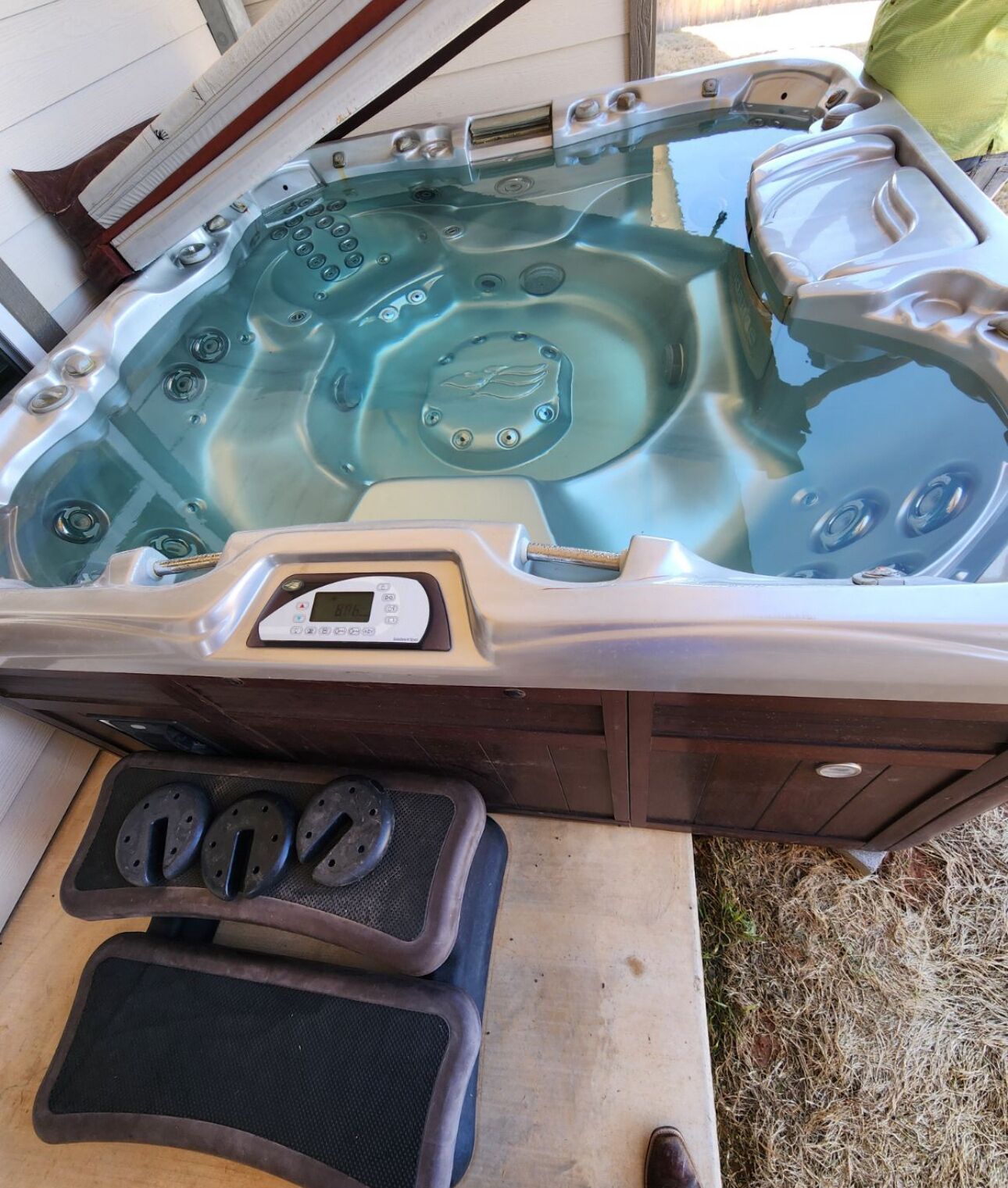 A hot tub with a control panel, two footrests, and a wooden deck.