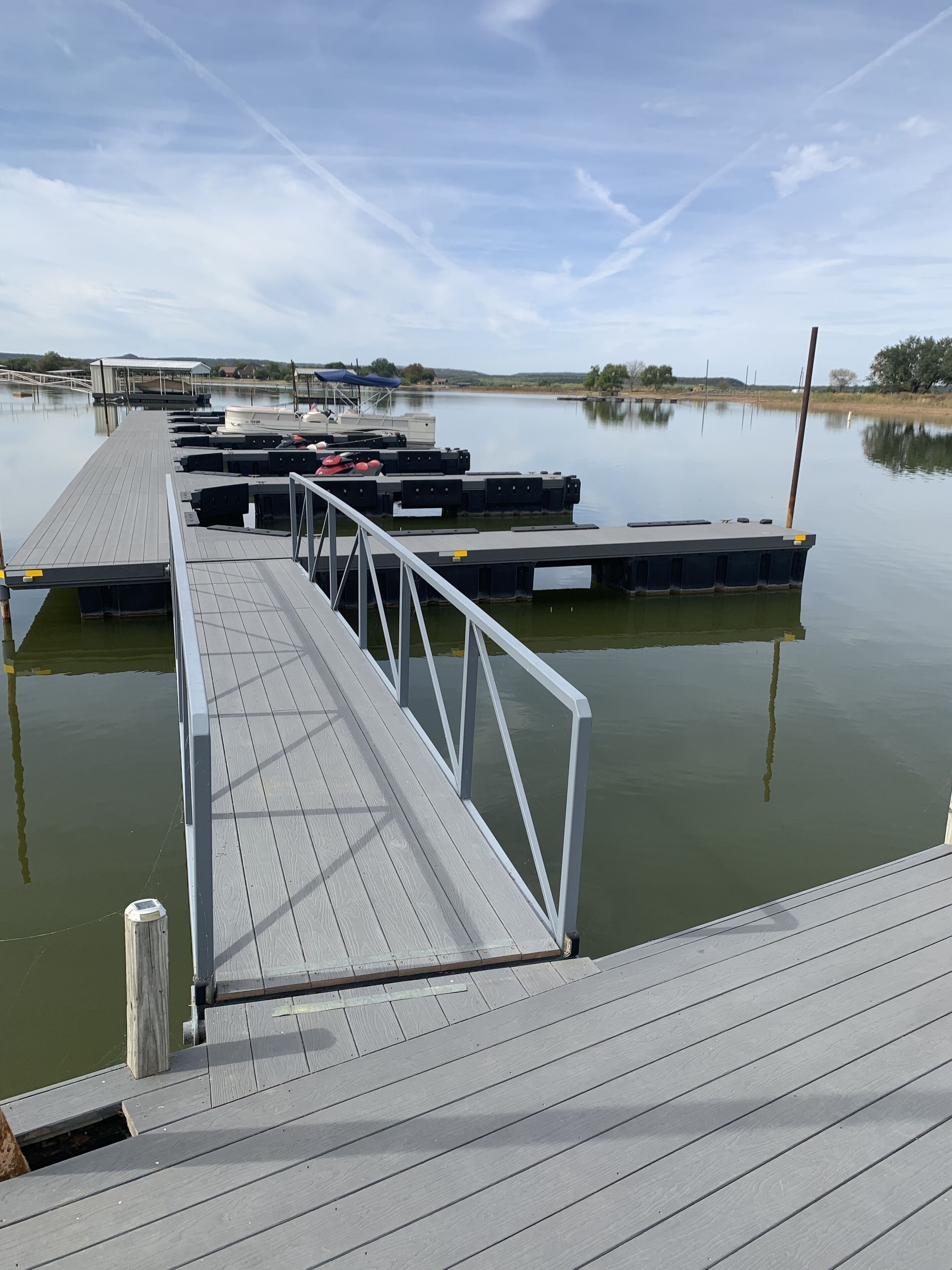 A wooden dock extending into calm water with boats docked.