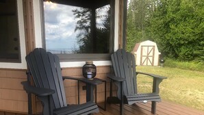 Zwei Adirondack-Stühle auf einer Holzterrasse mit einer Fußmatte.