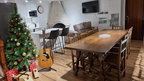 A modern living room with a wooden dining table, a Christmas tree, and a guitar. - Casa Rural Margarita (Peñaranda de Duero)