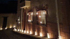 A building with a brick facade, a balcony, and a series of lit candles along the front steps. - Casa Rural Margarita (Peñaranda de Duero)
