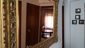 A room with a large ornate mirror reflecting a door and a round table with a chair. - Casa Rural Margarita (Peñaranda de Duero)