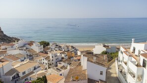A coastal town with white buildings, a beach, and the sea.