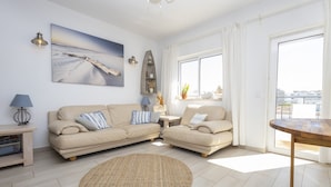 Una sala de estar moderna con un sofá beige, un tapete redondo, una mesita, una lámpara y un cuadro en la pared.