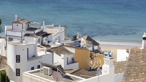 Un bâtiment situé sur la côte, doté de plusieurs terrasses, d’une antenne parabolique et offrant une vue sur la plage.