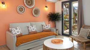 A living room with a light blue sofa, patterned cushions, a round coffee table, and a large potted plant. - Appartement vue Mer, Accès Direct Plage D'orient Bay (Orient-Bay)