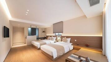 A hotel room with two beds, a small table, a mirror, and a wall-mounted TV.