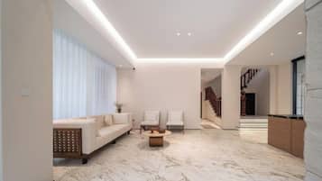 Un salon moderne avec un sol en marbre, un canapé, deux fauteuils et une table basse.