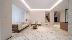 A modern living room with a marble floor, a sofa, two chairs, and a coffee table.