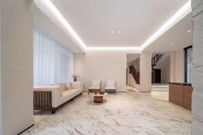 A modern living room with a marble floor, a sofa, two chairs, and a coffee table. - Shenweilou Hotel (Yueqing)