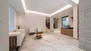 Un saló modern amb terra de marbre, sofàs blancs i una taula de centre.