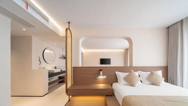 Habitació d'hotel moderna amb llit, taula de nit i televisió integrada.