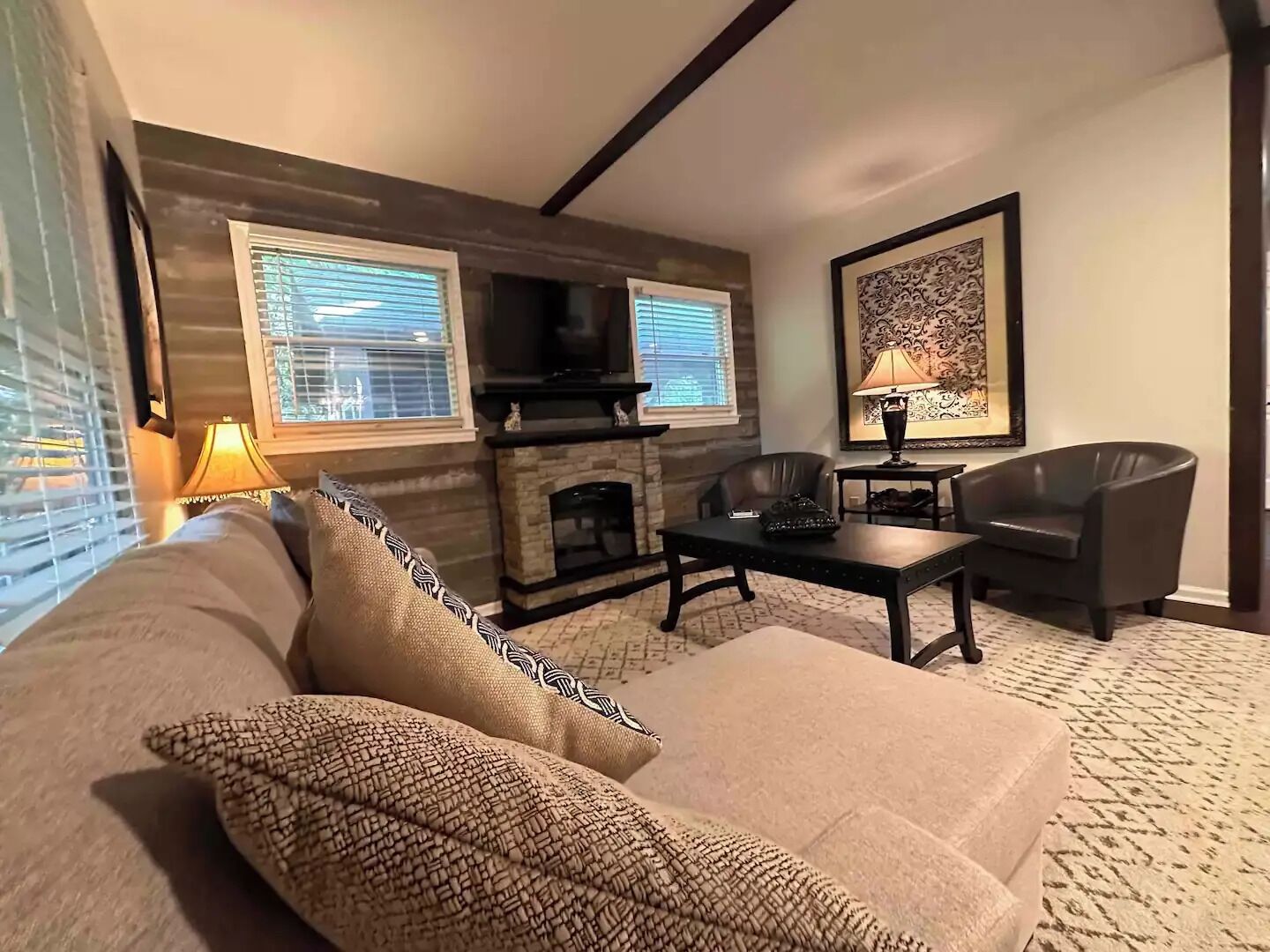 A cozy living room with a fireplace, a sofa, two armchairs, and a coffee table.