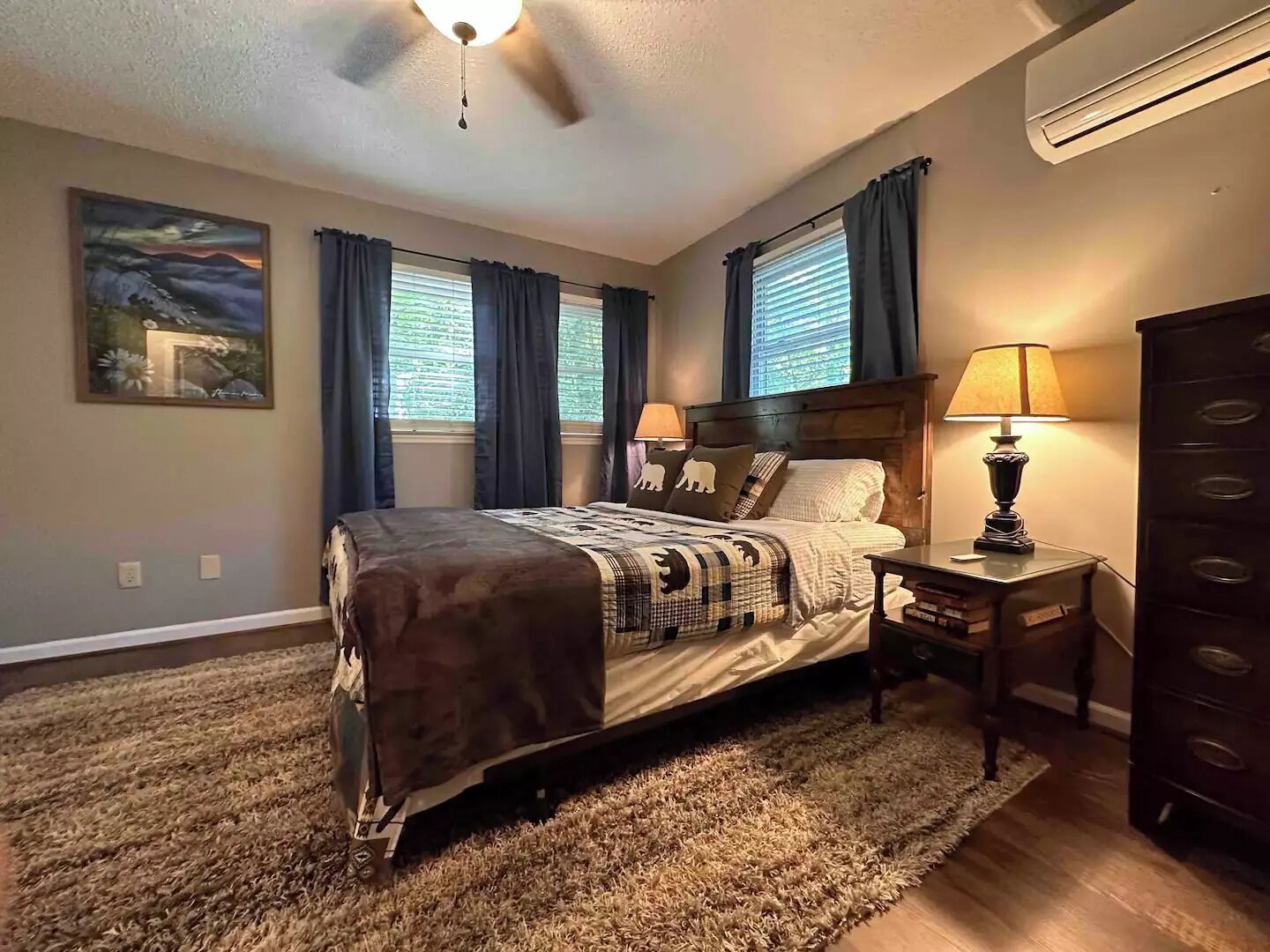 A bedroom with a bed, two bedside lamps, a dresser, and a ceiling fan.