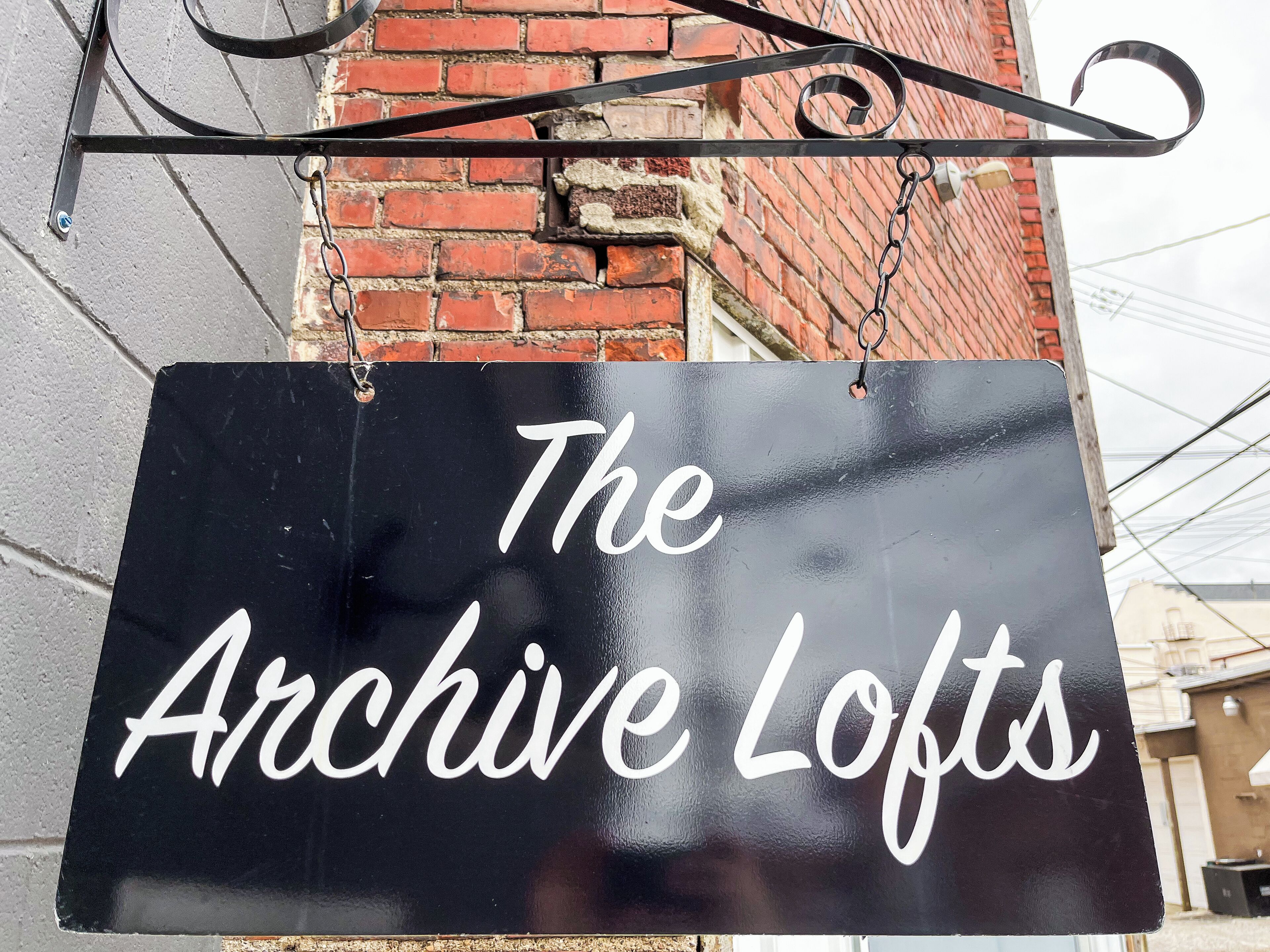 A black sign with white cursive text reading "The Archive Lofts".