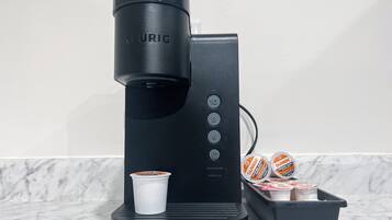 A Keurig coffee maker with a cup of coffee, a container of Dunkin' Donuts coffee pods, and a black tray.