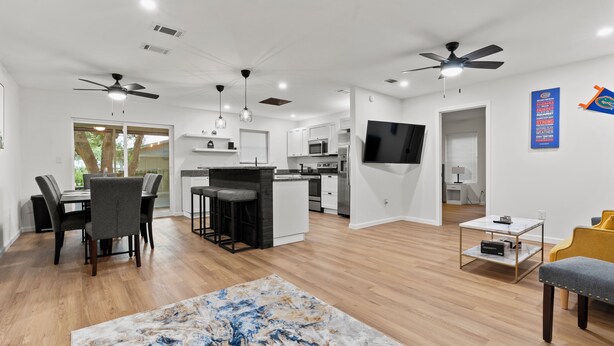A modern kitchen with white cabinets, a central island, and a flat-screen TV.