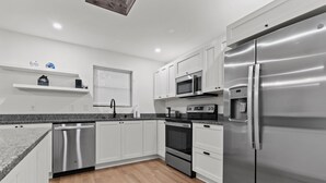 A modern kitchen with white cabinets, stainless steel appliances, and a granite countertop.