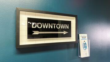 A framed sign with "DOWNTOWN" and an arrow pointing right, mounted on a teal wall.