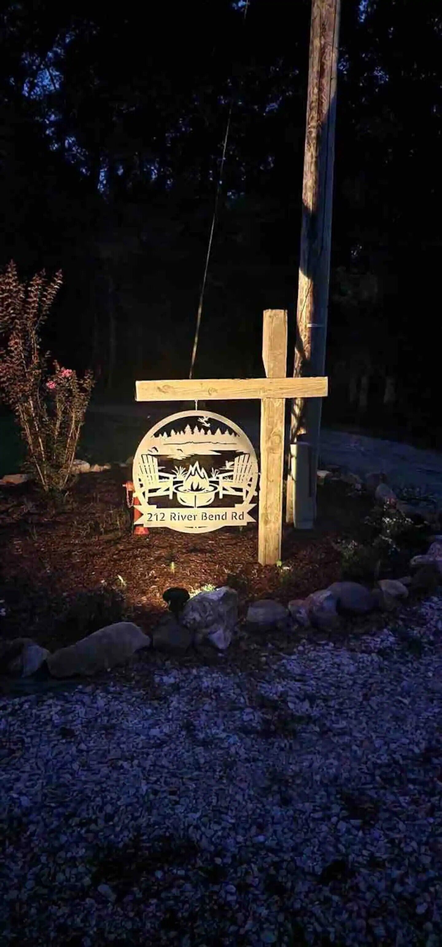 Uma placa de madeira com um desenho de paisagem e o texto '212 River Bend Rd'.