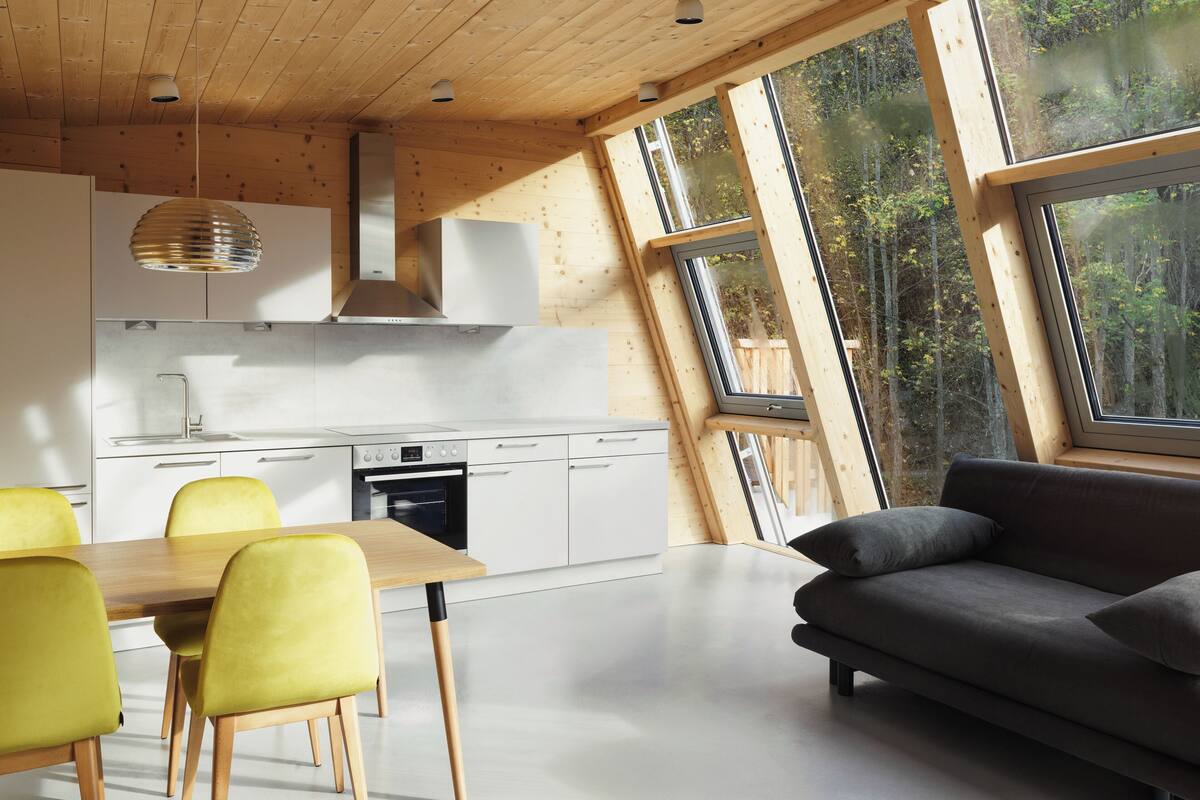 Eine moderne Küche mit Essbereich, großen Fenstern und einer Couch.