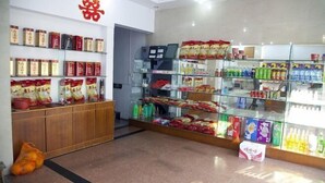 A store with shelves of snacks and beverages, a wooden counter, and a glass display case. - Red Moon Inn (Yueqing)