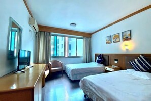 Habitación de hotel con dos camas, un escritorio, una silla, un televisor y una ventana con cortinas.