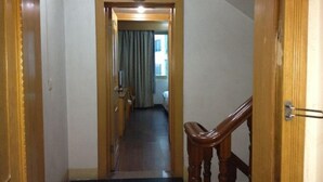 A narrow hallway with a wooden staircase leading to a room. - Red Moon Inn (Yueqing)