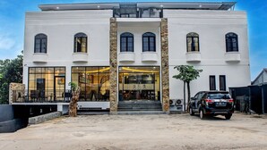 A modern building with a white facade, large windows, and a staircase leading to the entrance. - Capital O 92583 Raja Soeta Hostel Syariah (Bandar Lampung)