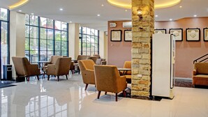 A spacious lobby with modern furniture, large windows, and a stone pillar. - Capital O 92583 Raja Soeta Hostel Syariah (Bandar Lampung)