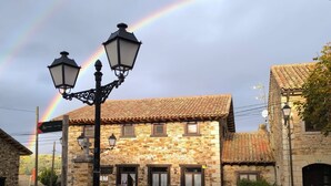 A stone building with a tiled roof, a paved courtyard, and a street lamp. - Posada Restaurante de Serrada (Puentes Viejas)