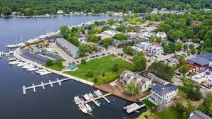 Vue aérienne d’une marina avec des quais, des bateaux et une zone résidentielle comprenant des maisons et de la verdure.