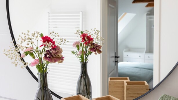 A bedroom with a large mirror, two glass vases with flowers, and wooden storage boxes. - Holiday home in the middle of the old town of Goslar for up to 6 people (Goslar)