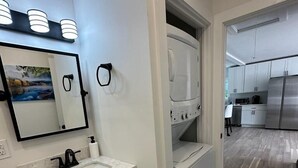 Un baño moderno con lavamanos blanco, espejo y toallero.