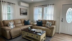 Una sala de estar con dos sofás color beige, una mesa de centro de madera y una alfombra gris.