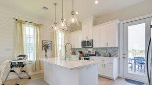 Una cocina moderna con armarios blancos, una isla grande e iluminación colgante.