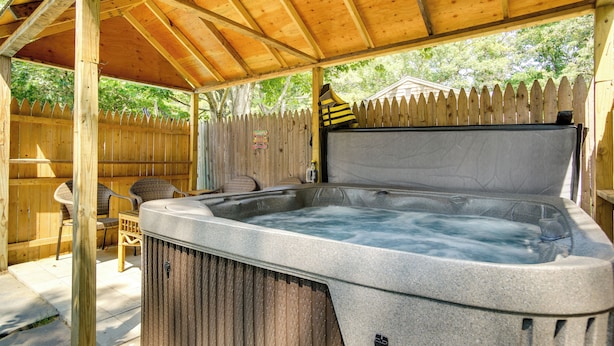 Een hottub onder een houten pergola, met een houten omheining op de achtergrond.