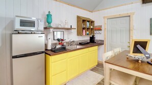 Una cocina con un refrigerador blanco, gabinetes amarillos, una encimera de madera, un microondas, un lavabo y una mesa de comedor con sillas.