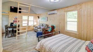 Een chalet met een hoogslaper, een bureau met computer, een leren bank en een eethoek.