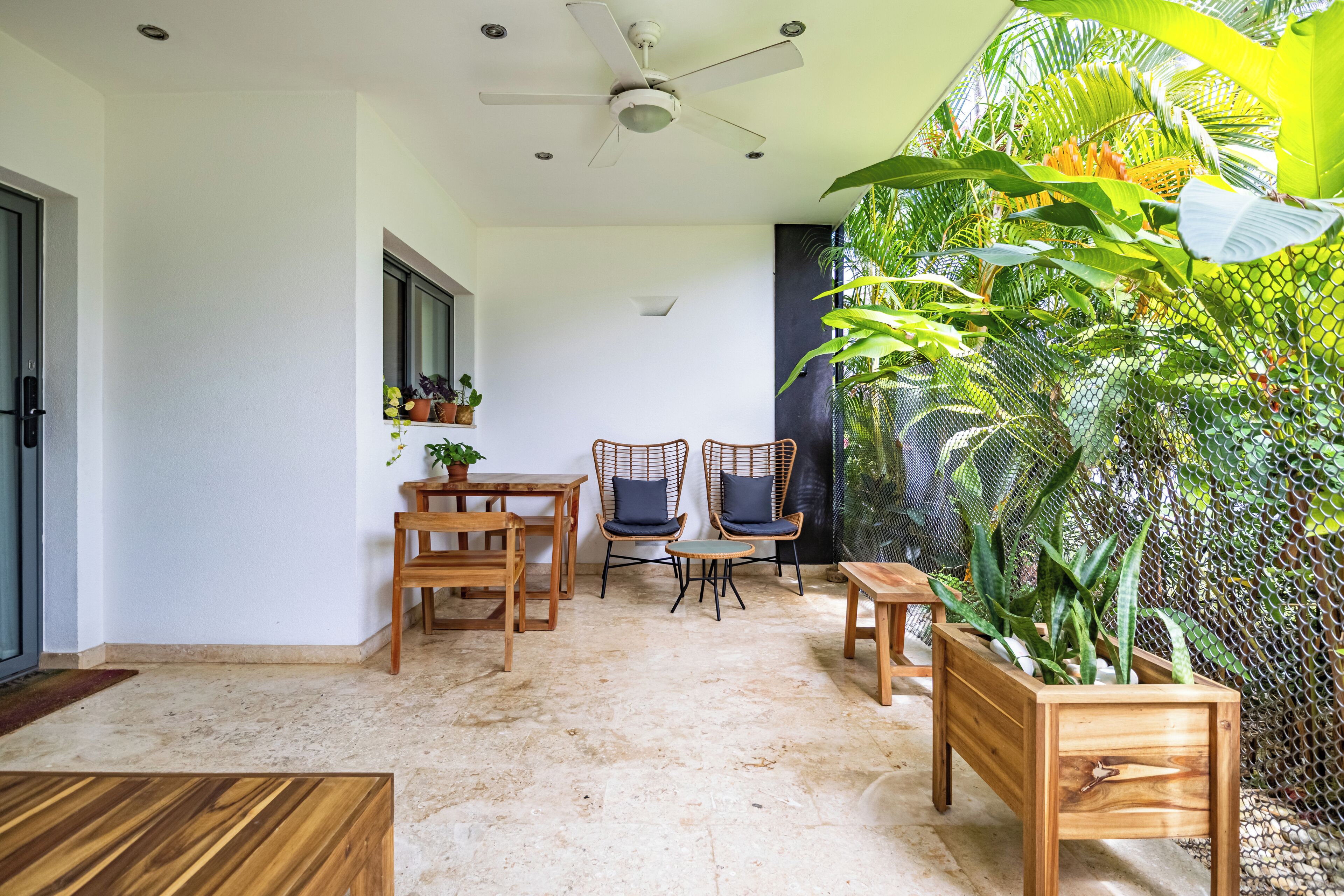 A room with a ceiling fan, wooden furniture, and a large potted plant.