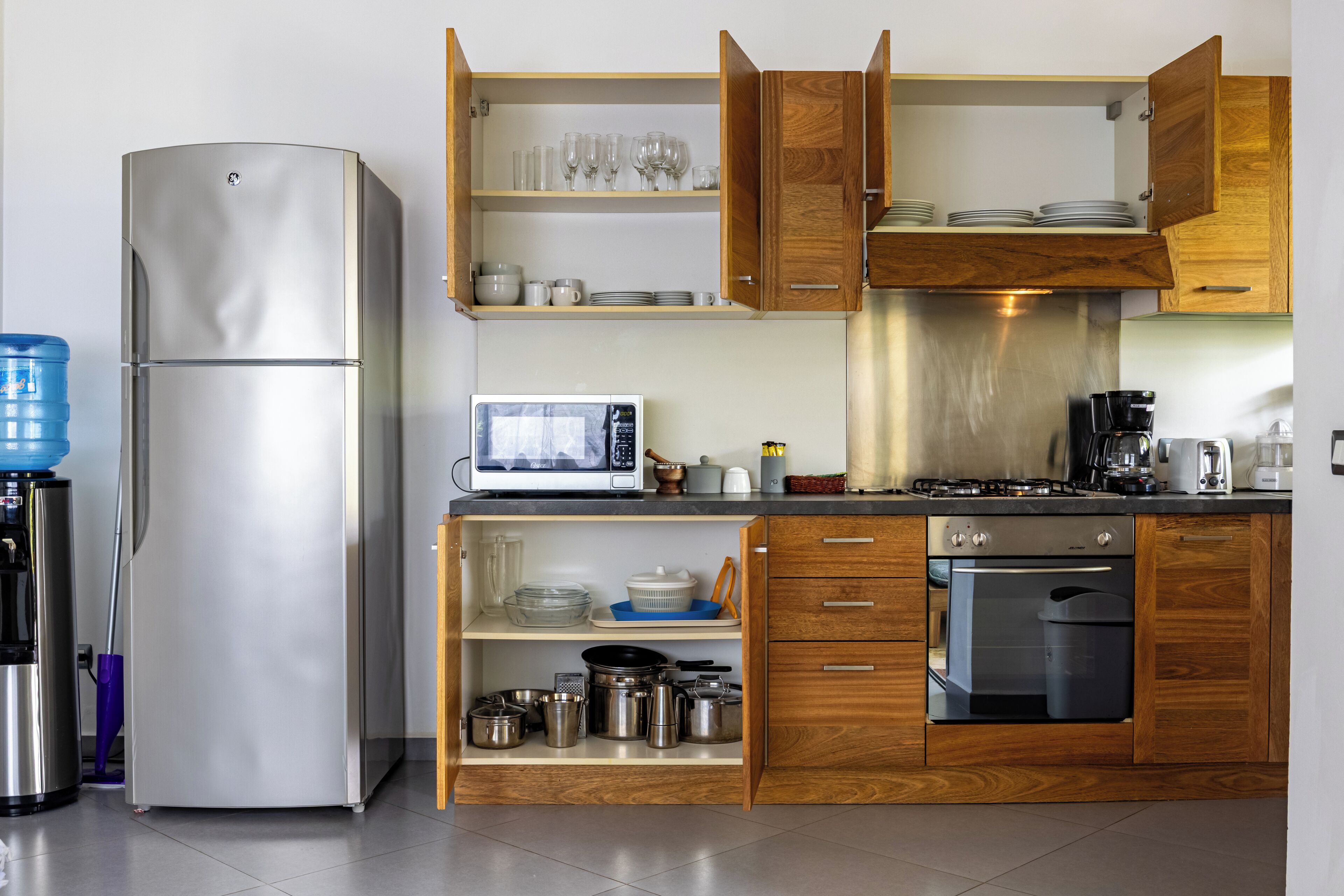 A modern kitchen with stainless steel appliances, wooden cabinets, and a built-in microwave.