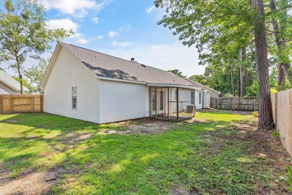 A single-story house with a sloped roof, a covered patio area, and a fenced backyard. - Once Upon a Tide/2 King Beds/Centrally Located (Brunswick)
