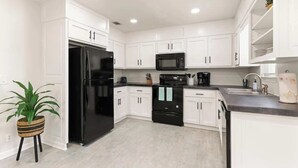 A modern kitchen with white cabinets, a black refrigerator, a microwave, and a stove. - Once Upon a Tide/2 King Beds/Centrally Located (Brunswick)